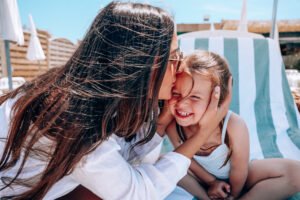 M&egrave;re embrassant sa fille sur un transat &agrave; La R&eacute;serve Plage, Grau du Roi