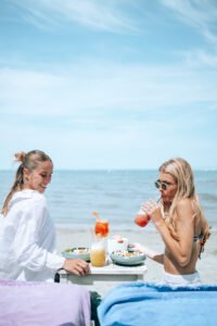 Deux femmes d&eacute;gustant un repas avec cocktails au bord de l&rsquo;eau &agrave; La R&eacute;serve Plage, Grau du Roi